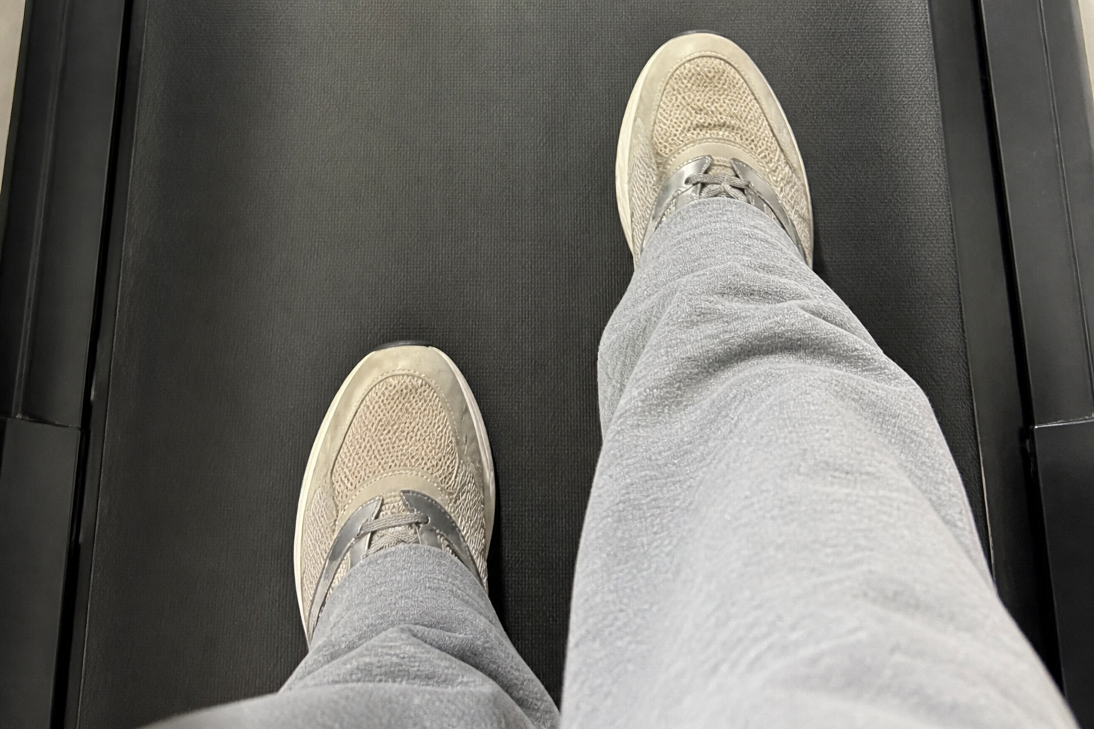 Walking pad under a standing desk in a bright home office